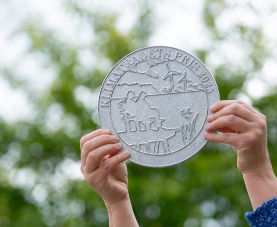 En person håller upp plaketten för Klimatpriset 2025.