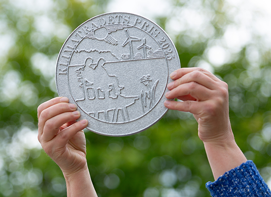 En person håller upp plaketten för Klimatpriset 2025.